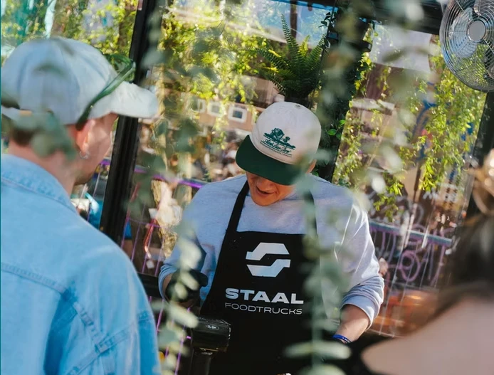 Medewerker van Staal Foodtrucks aan het werk in een foodtruck op een evenement